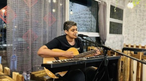 Kay performing with guitar and keyboard at a charity event
